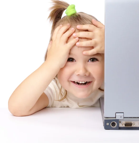 Cute little girl is looking out from her laptop — Stock Photo, Image