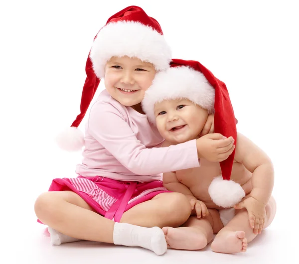 Duas crianças vestindo bonés de Natal vermelho e sorriso — Fotografia de Stock