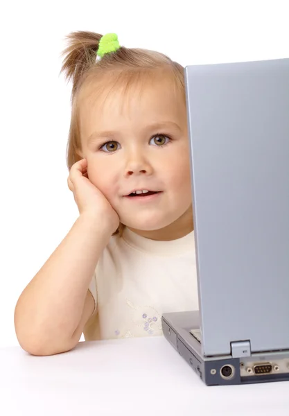 Carino bambina sta guardando fuori dal suo computer portatile — Foto Stock
