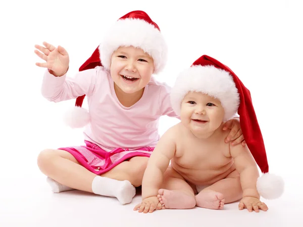 Kırmızı Noel kapaklar ve gülümseme giyen iki çocuk — Stok fotoğraf