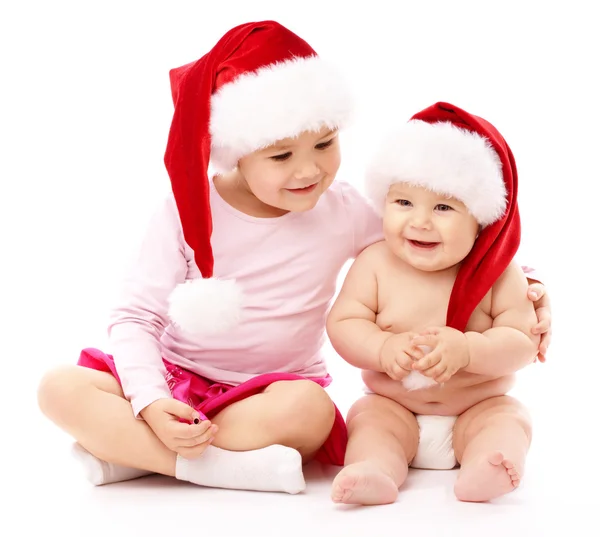 Δύο παιδιά της φορώντας κόκκινα Χριστούγεννα caps και χαμόγελο — Φωτογραφία Αρχείου