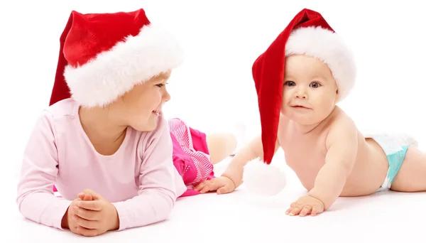 Két gyermeke visel piros karácsonyi sapkák és mosoly — Stock Fotó