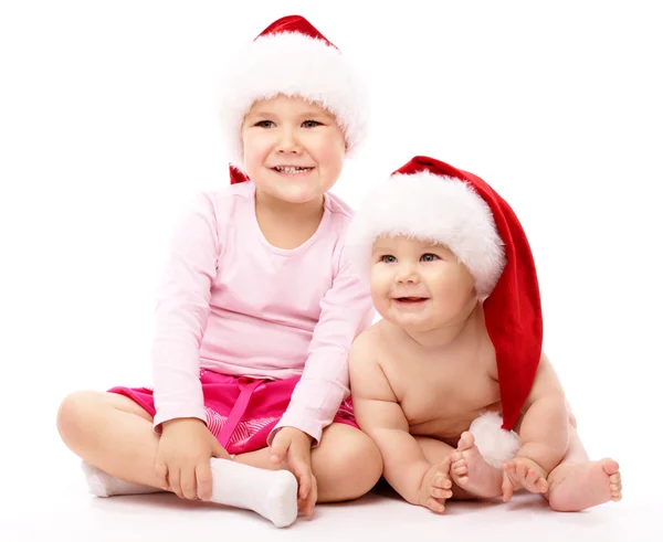Two children wearing red Christmas caps and smile Stock Photo