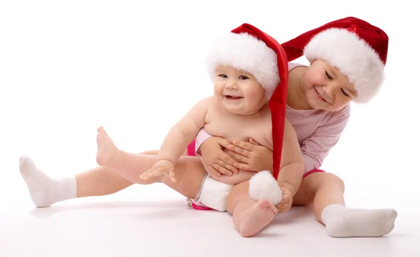Two children wearing red Christmas caps and smile — Stock Photo, Image