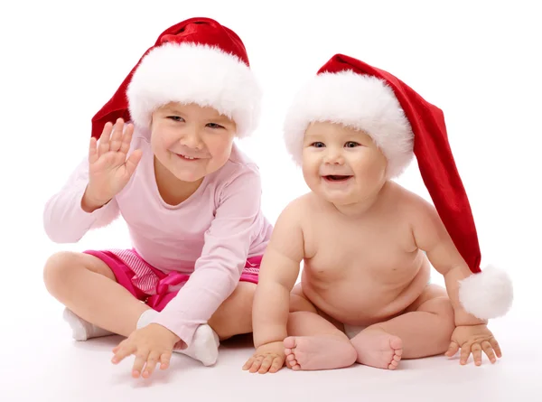 Two children wearing red Christmas caps and smile Stock Picture