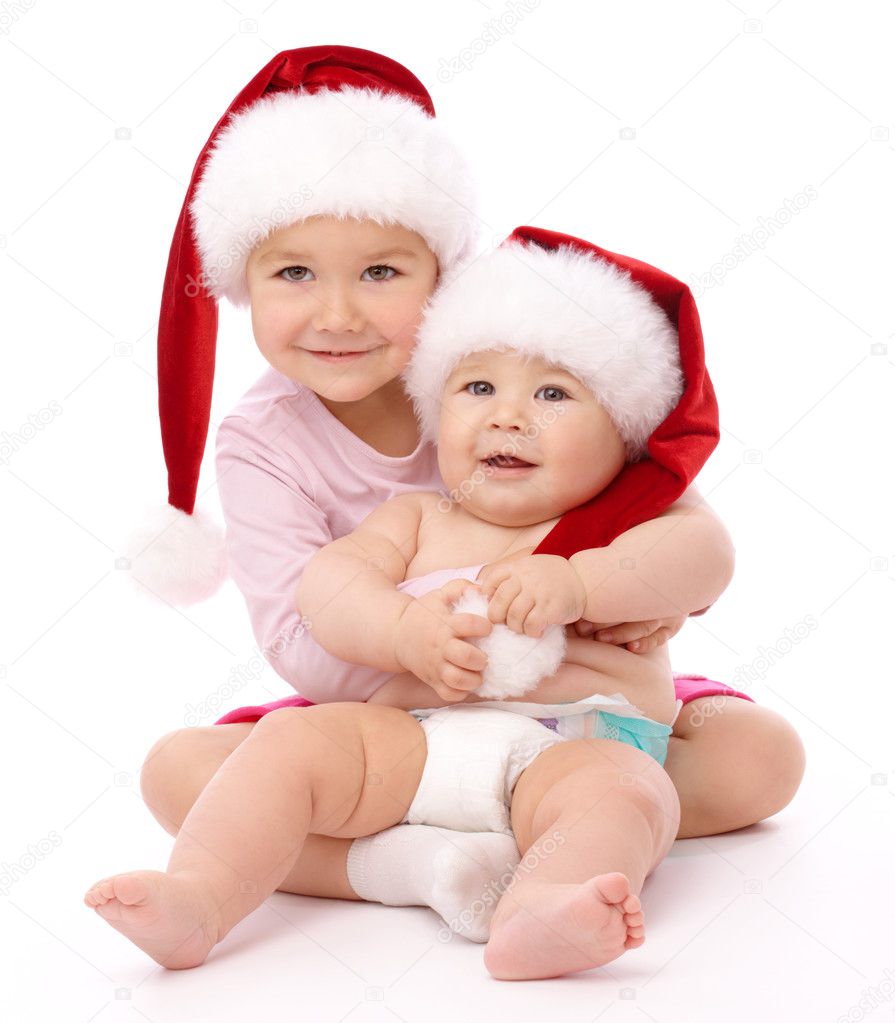 Two children wearing red Christmas caps and smile
