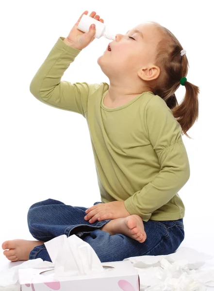 Menina Pulverizando Nariz Com Spray Nasal Enquanto Sentada Chão Isolada — Fotografia de Stock