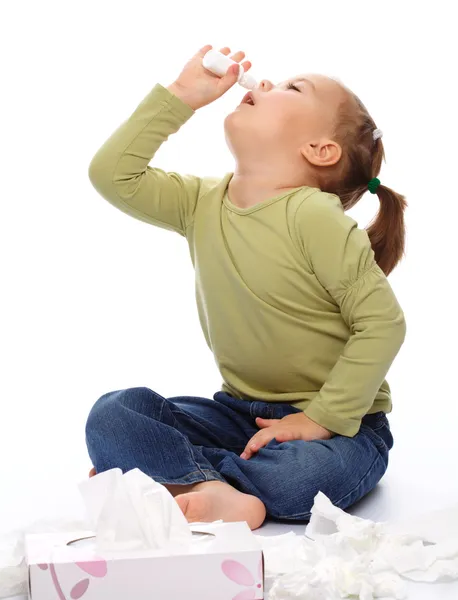 Menina Pulverizando Nariz Com Spray Nasal Enquanto Sentada Chão Isolada — Fotografia de Stock