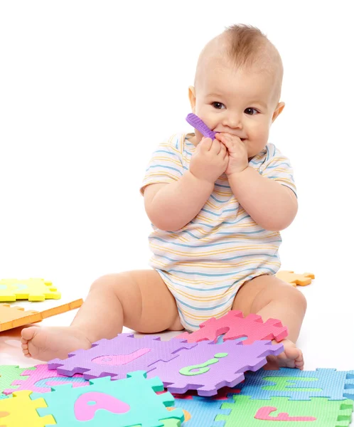 可爱的小男孩在玩字母表 坐在地上 隔离白上咬一封信 — 图库照片
