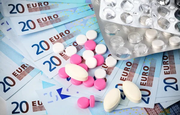 stock image Few pills over Euro money, high prices for drugs concept