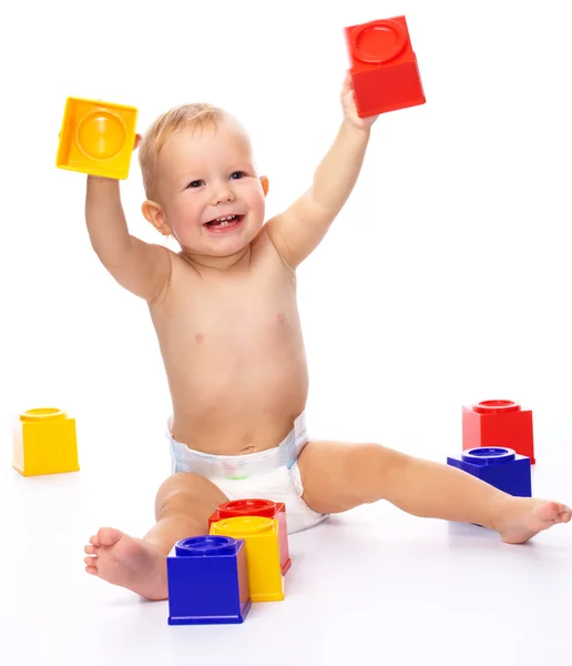幸せな小さな男の子は 白で隔離された床に座っている間の建設用れんがで遊んでください — Stockfoto
