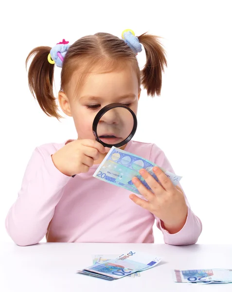 Девушка смотрит на банкноту евро с помощью увеличителя — стоковое фото