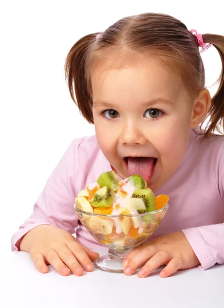 Little girl licks fruit salad — Stock Photo, Image