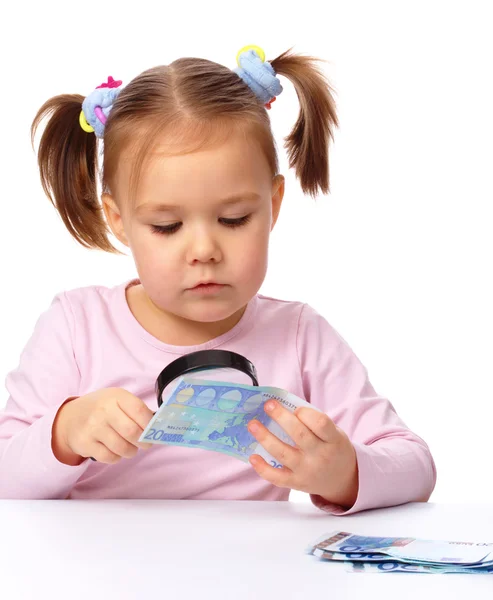 Girl is looking at euro banknote using magnifier — Stock Photo, Image