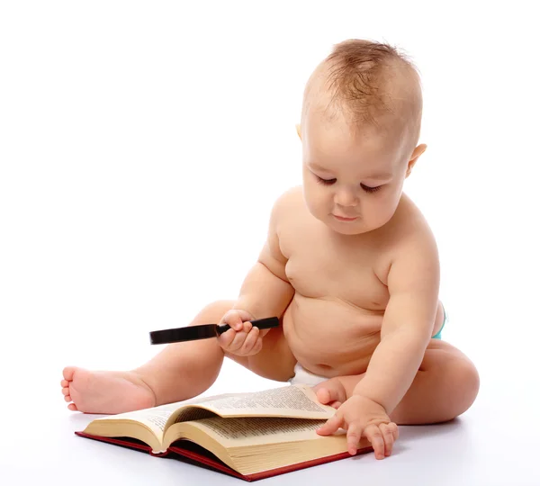 Little child play with book and magnifier Royalty Free Stock Photos