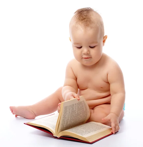 Malé dítě hrát s knihou a Lupa — Stock fotografie