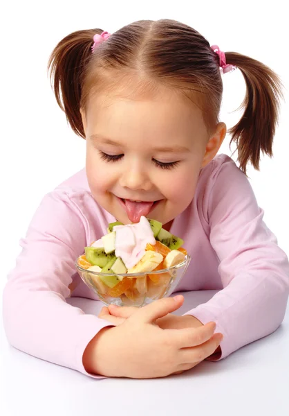 Malá dívka olizuje ovocný salát — Stock fotografie