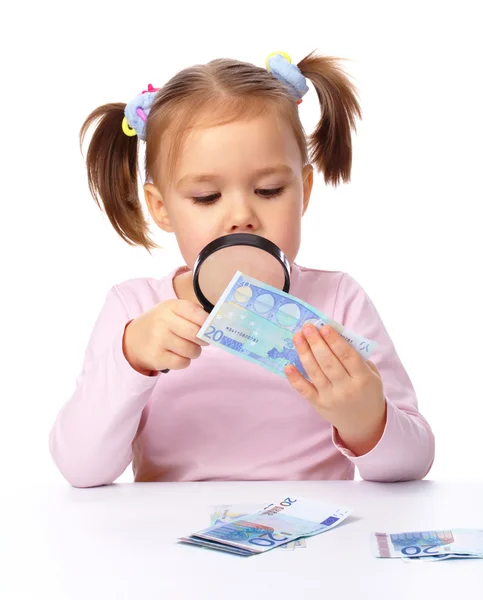 stock image Girl is looking at euro banknote using magnifier