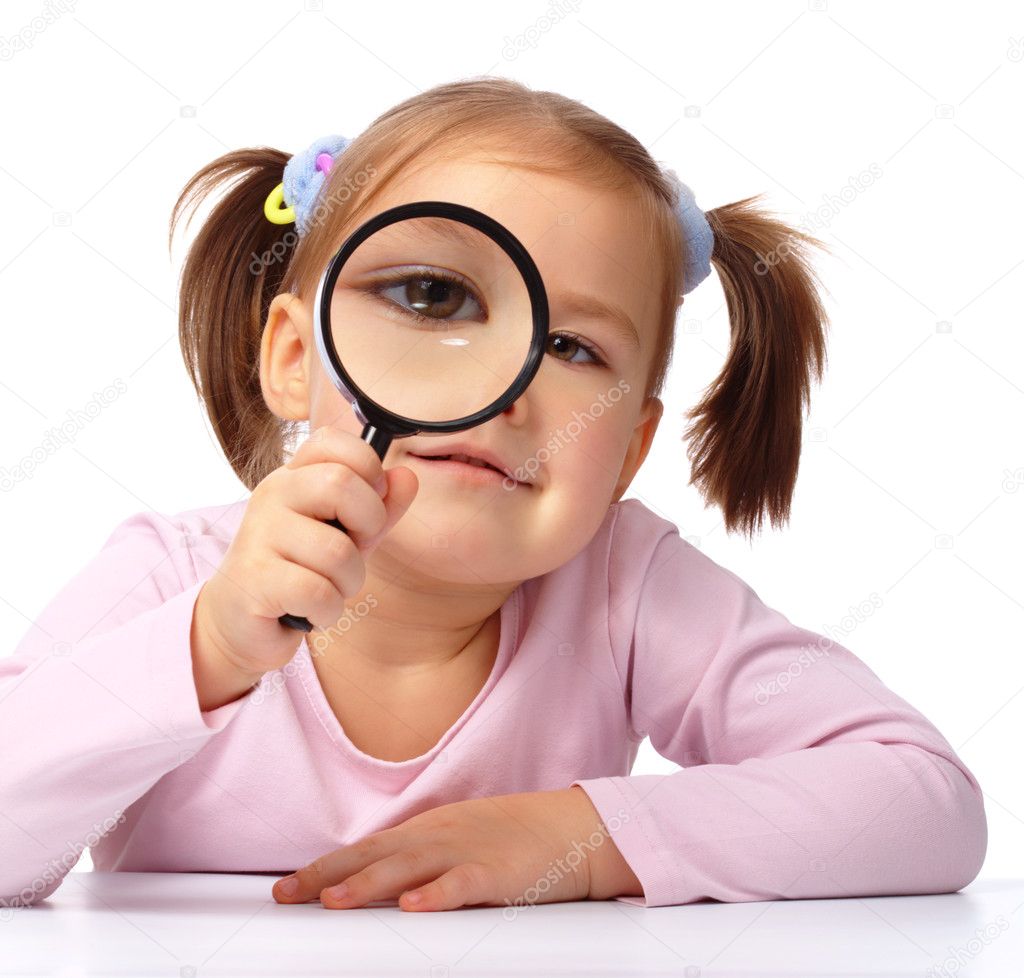 Curious girl is looking through magnifying glass
