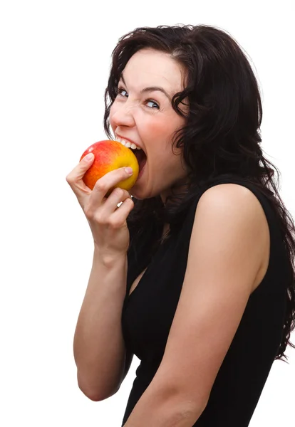 Jovem mulher atraente está mordendo uma maçã — Fotografia de Stock