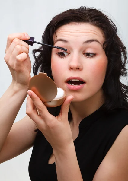 Woman is applying mascara while looking in mirror — Stock Photo, Image