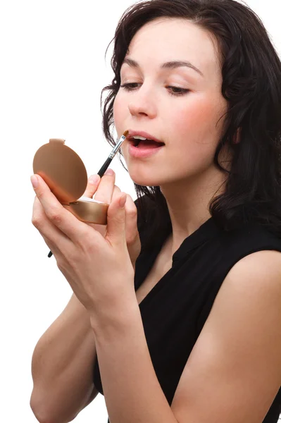 Frau trägt Lipgloss auf, während sie in Spiegel schaut — Stockfoto