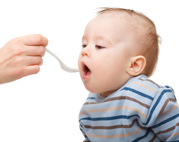 Menino bonito está sendo alimentado usando colher — Fotografia de Stock