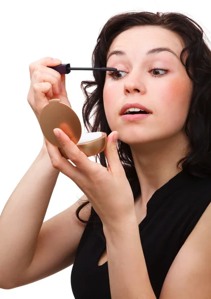 Woman is applying mascara while looking in mirror — Stock Photo, Image