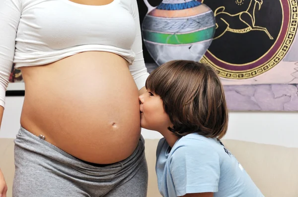 Young boy kissing pregnant belly — Stock Photo, Image
