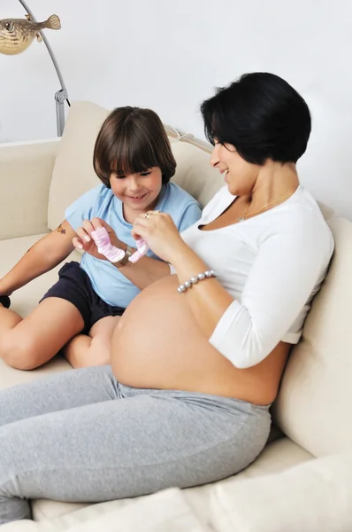 Беременная женщина и ее маленький сын сидят на диване — стоковое фото