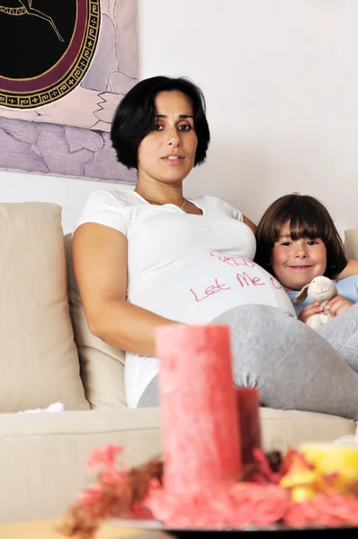 妊娠中の女性と彼女の若い息子ソファーに座っていた — ストック写真