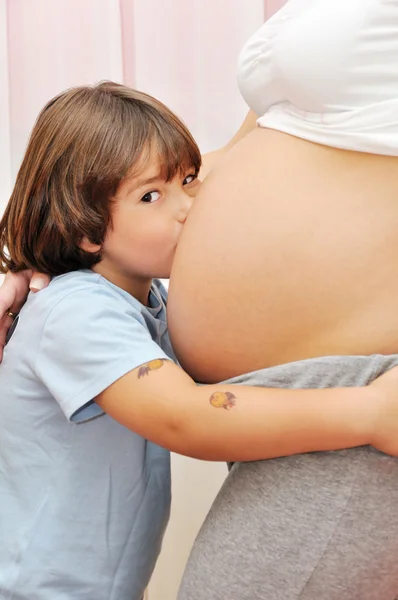 Jeune garçon embrasser ventre enceinte — Photo