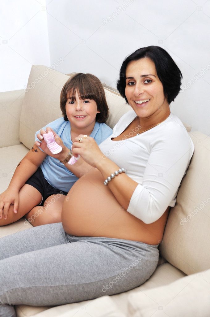 Pregnant woman and her young son sitting on sofa