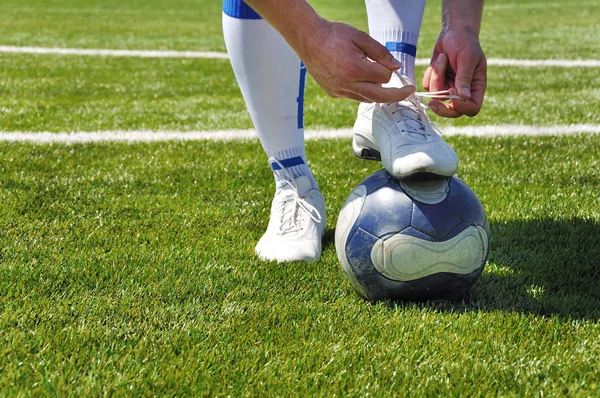 Человеческая нога и футбольный мяч на травяном поле — стоковое фото