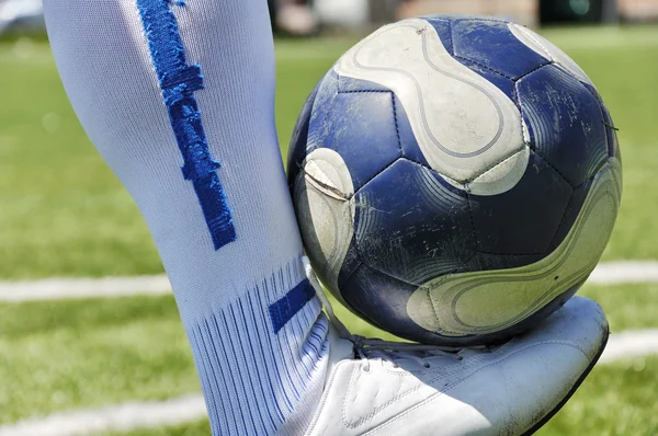 Perna humana e bola de futebol no campo de grama — Fotografia de Stock