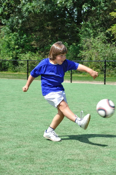 Мальчик стреляет футбольным мячом — стоковое фото