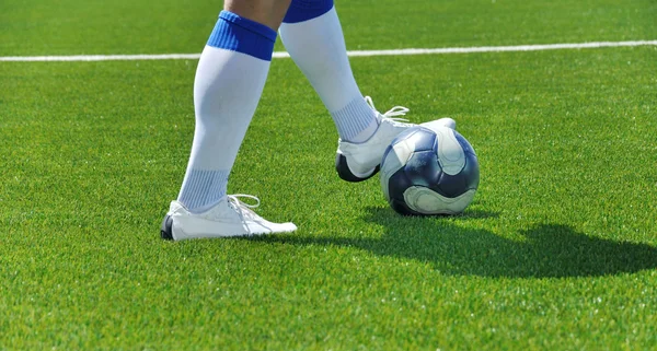Футболист и мяч на травяном поле — стоковое фото