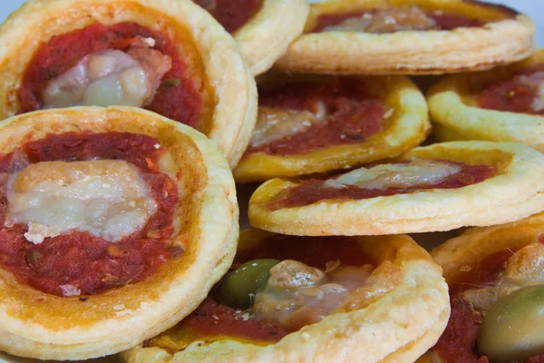 Mini-pizzor bakgrund med oliver, ost och tomat sås redo att äta — Stockfoto