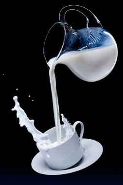 Milk flows from a jug in a cup