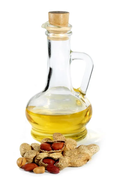 Oil in the vessel and peanuts on a white background — Stock Photo, Image