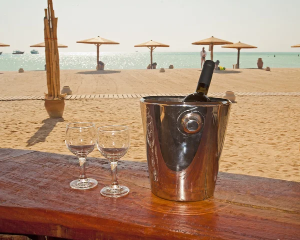 Wine bottle and glasses on a beach bar — Stock Photo, Image