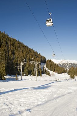 Teleferik lift üzerinde ağaçların arasından bir kayak pisti