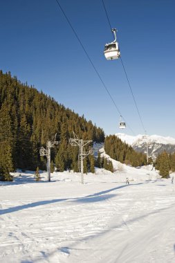 Cable car lift over a ski slope through the trees clipart