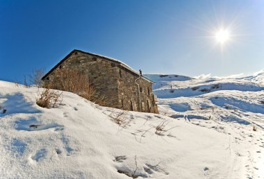 Karda bir dağın üzerinde tuğla hut