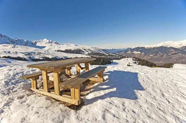 Piknikový stůl na vrcholu zasněžené hory — Stock fotografie