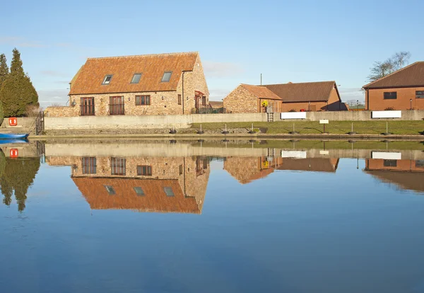 Дома рядом с рекой с отражением — стоковое фото