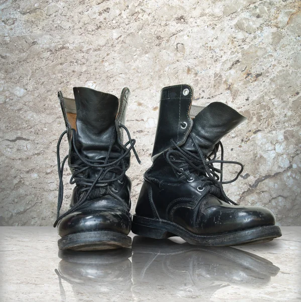 Old black boot on white marble — Stock Photo, Image