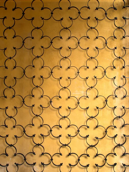 Металлический орнамент на старой гранжевой желтой стене — стоковое фото