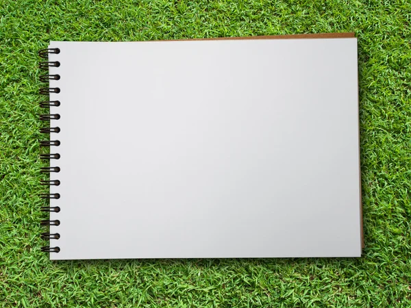 Note book on green grass — ストック写真