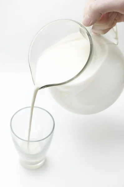Man hand flyter mjölk från burk i glas — Stockfoto